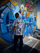 Man standing in front of a colorful graffiti mural on a wall.